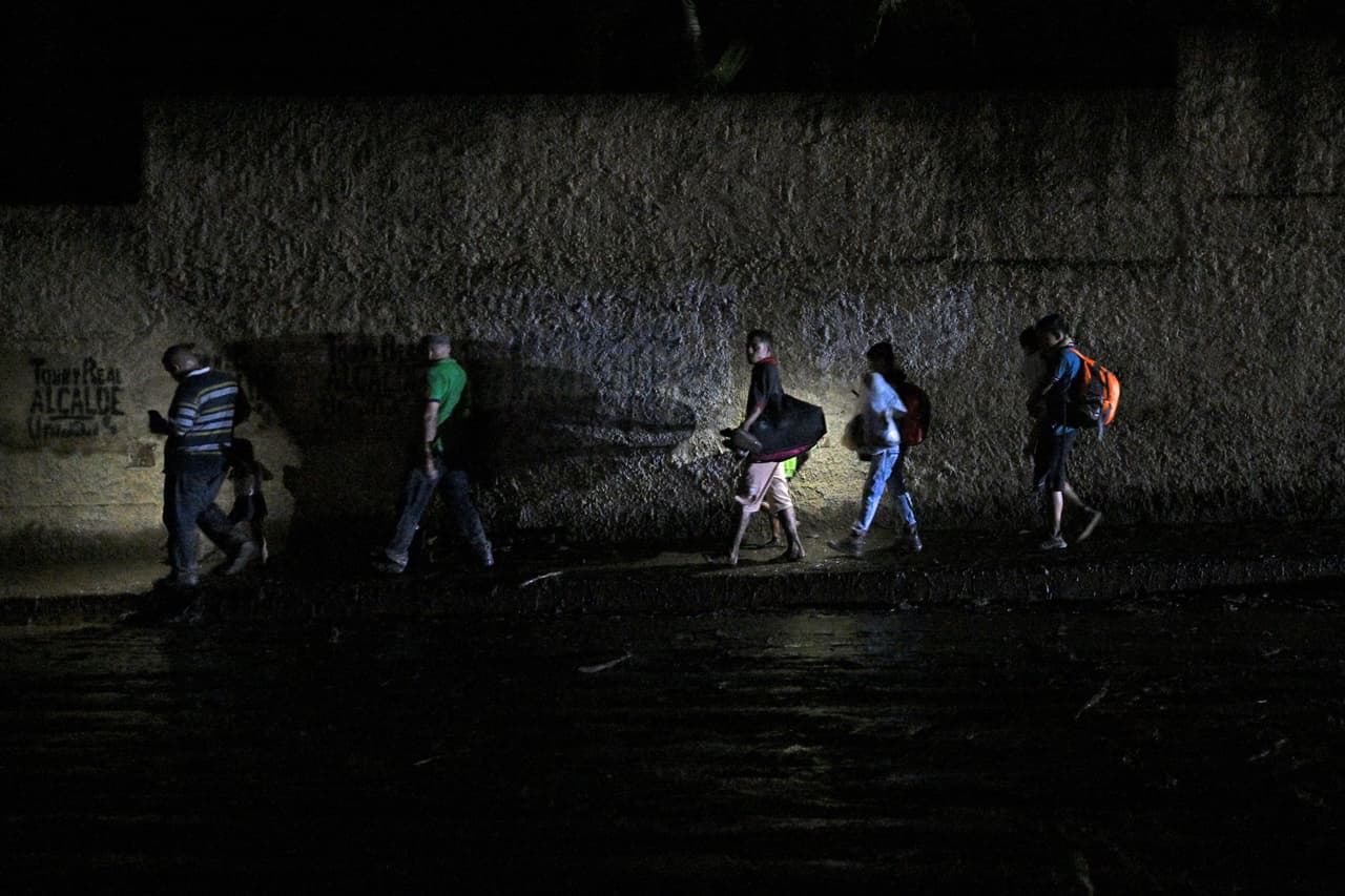 Gente camina por una calle de El Castaño llevando algunas pertenencias entre sus manos. José Dos Santos, de 56 años, se refugió con su familia en la parte más alta de su casa. "Veía para la montaña que la lluvia estaba fuerte, escuchamos un estruendo y cuando veo se está metiendo el agua por las ventanas y agarré a mi gente y nos montamos", relató a la AFP.
<br>