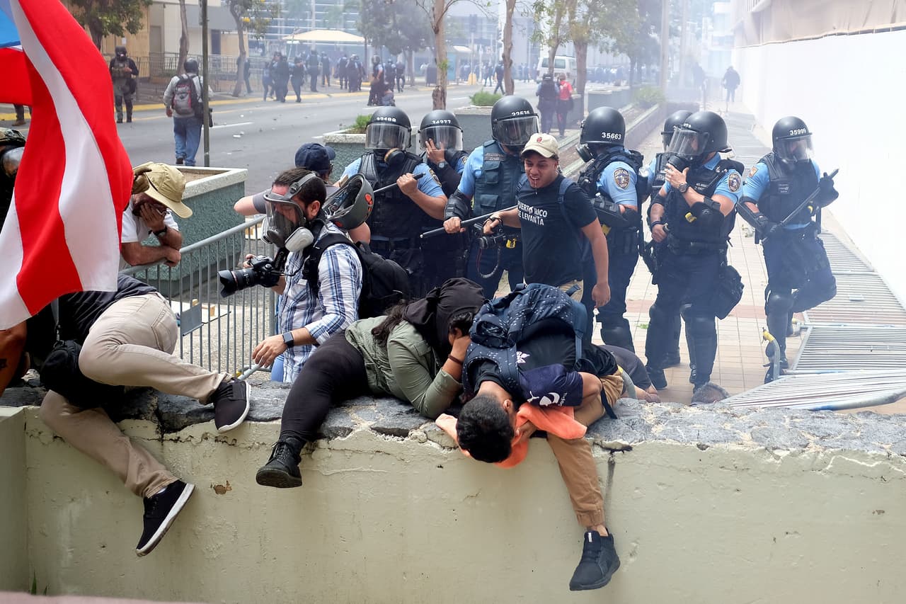 Manifestantes afectados por los gases lacrimógenos intentan escapar de la policía antimotines.