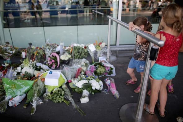 Un par de niñas admira la ofrenda floral que adorna la entrada al aeropuerto de Schiphol, en Ámsterdam