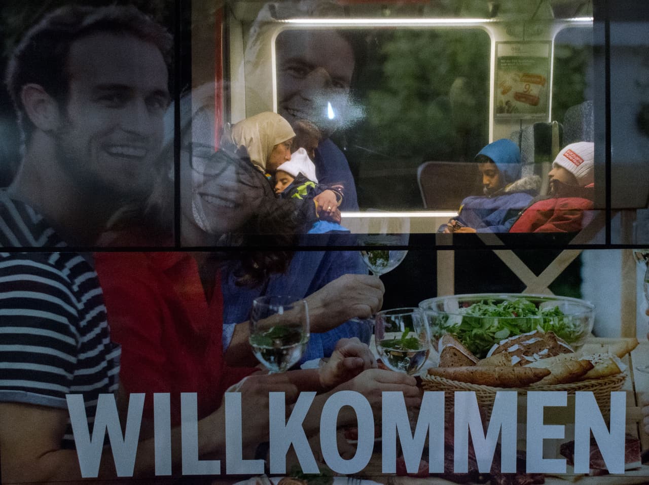 <b>Capítulo 6. Bienvenidos a Europa.</b> Un nuevo tren llega. Va decorado con unos grandes rótulos de publicidad que ocupan todo el exterior del vagón. “Willkomen”, dice parte del texto rodeado por grandes caras impresas de jóvenes rubios sonrientes sentados a una mesa. El fotoperiodista se desespera cada vez que se abre y cierra la puerta corredera automática, que tapa el cartel publicitario, con la entrada y salida de voluntarios repartiendo botellas de agua y algo de comida a los felices y cansados pasajeros. Enmarcada por el colorido anuncio, una madre se instala en su asiento con dos niños y un bebé. Finalmente se sienta y abraza con ternura al bebé. La cámara registra el instante preciso que el periodista esperaba con ansiedad.
<b><a href="http://huelladigital.univisionnoticias.com/crisis-refugiados-javier-bauluz/capitulo-6/">(VER ESPECIAL COMPLETO).</a></b>