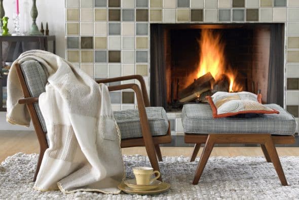 Incluyen el cálido fuego de una chimenea, un sofá con varias mantas tejidas, muebles de madera y colores que remiten a la naturaleza.