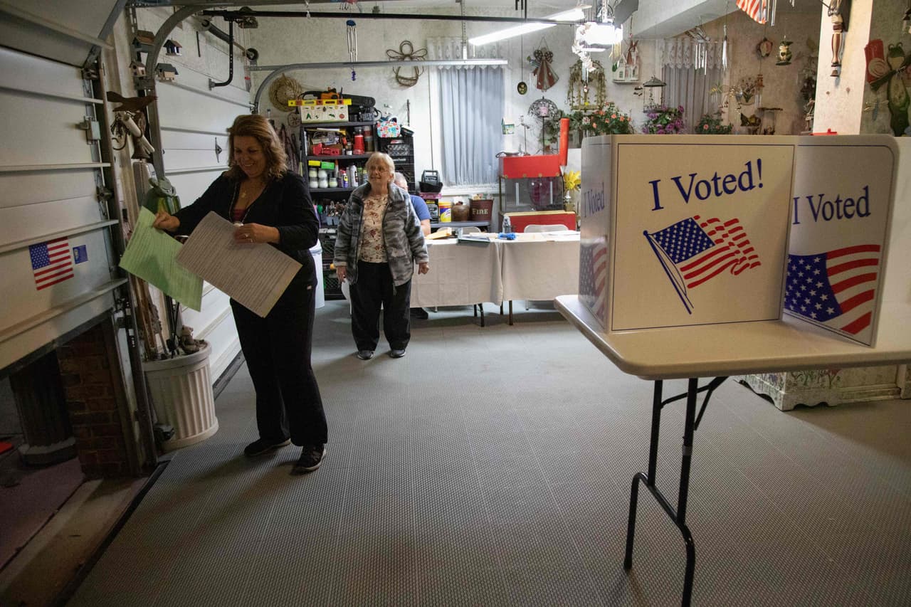 Marlo Miller (izquierda), secretaria de la mayoría, y Rose English, secretaria de la minoría, preparan un lugar de votación dentro del garaje de Miller antes de que abran las urnas, en Pittsburgh, Pensilvania.