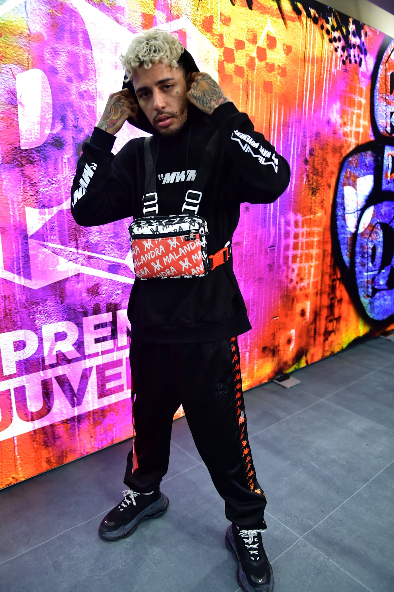 Dalex también llegó en ropa deportiva, él combinó el negro con el rojo, color que destacaba en la peculiar bolsa que llevaba colgada en la parte delantera de su cuerpo.