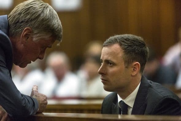 Pistorius escucha a uno de sus abogados defensores este lunes en el Tribunal Superior de Pretoria.