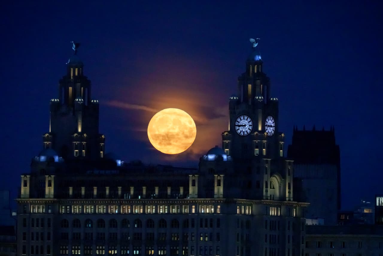 La luna azul llena se eleva detrás del Royal Liver Building y las estatuas de Liver Bird en Liverpool, Reino Unido.