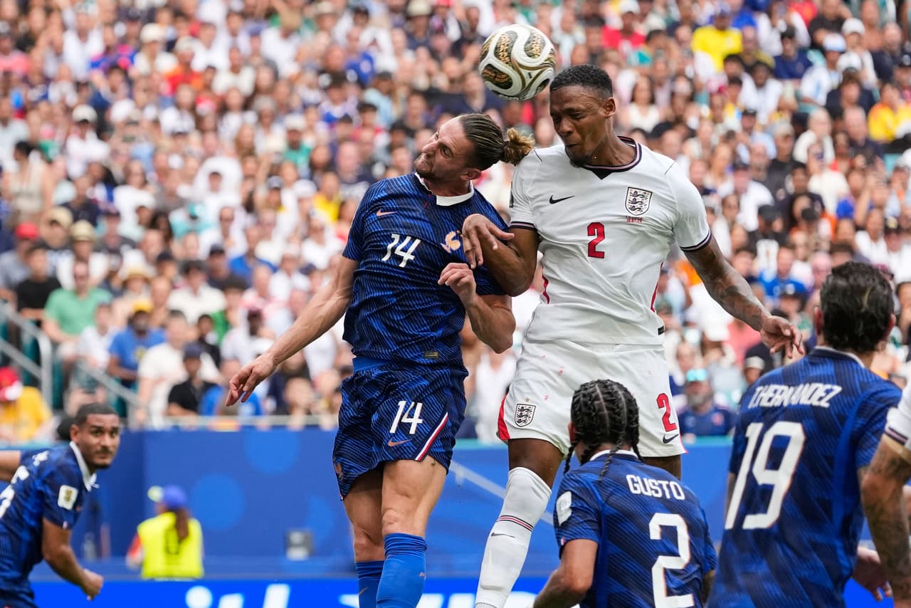 Ezri Konsa (2) de Inglaterra anota el segundo gol de su equipo de un tiro de esquina mientras Adrien Rabiot (14) de Francia defiende durante el partido por el tercer puesto de la Copa Mundial entre Francia e Inglaterra en Miami Gardens, Florida, el sábado 18 de julio de 2026.
