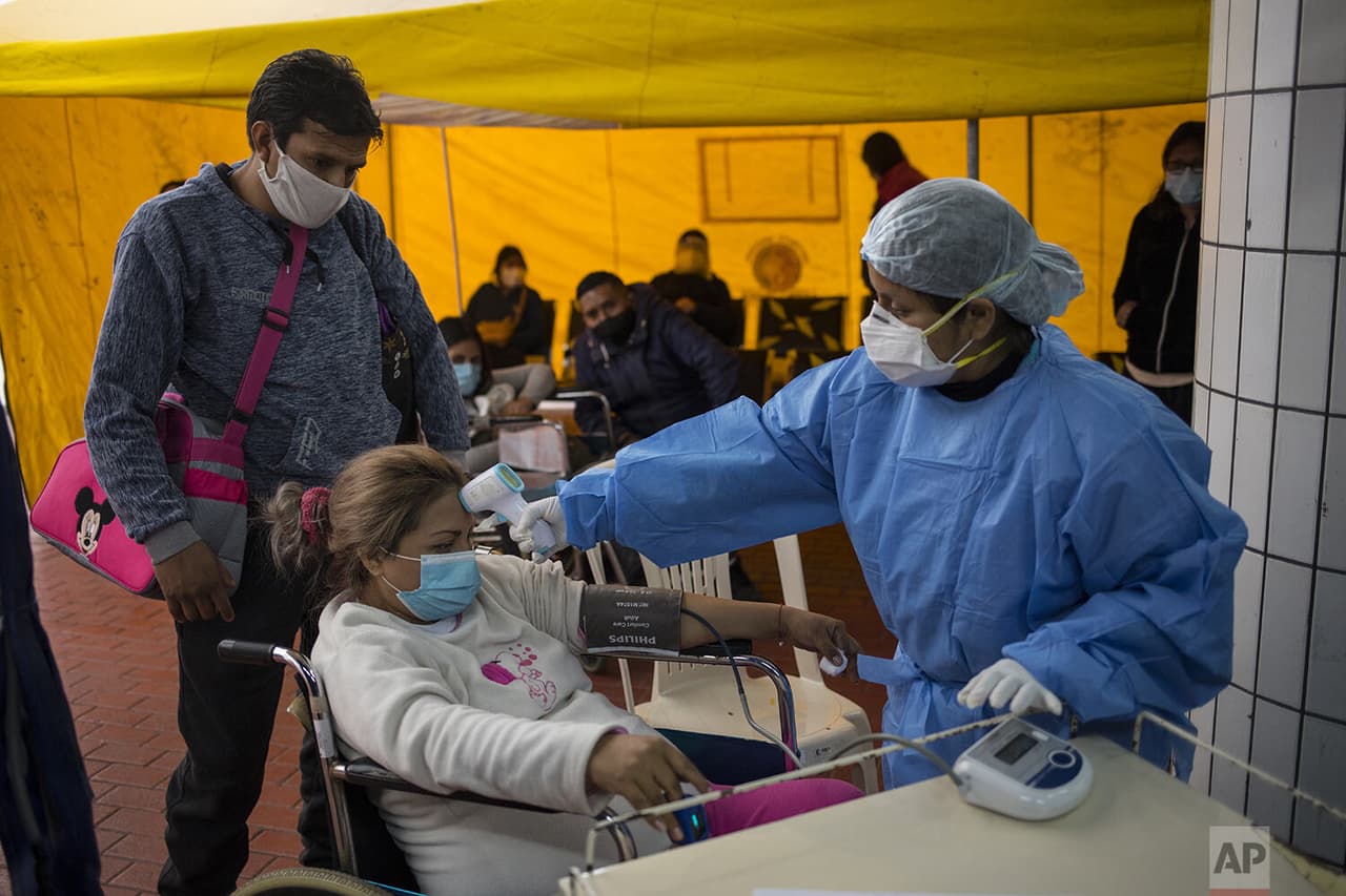 Una trabajadora de la salud mide la temperatura corporal de Luisita Hermosillo, de 32 años, como 
<b>parte de un chequeo inicial para identificar si está infectada con el coronavirus</b>, en un punto de entrada habilitado para recibir mujeres embarazadas.
