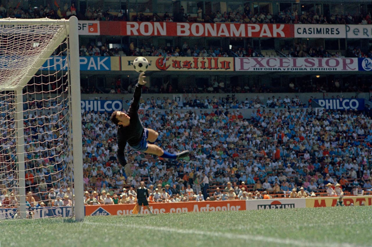 <b>Empate sin goles</b>
<br>- El conjunto mexicano no pudo celebrar una victoria junto a su afición en la cancha del Estadio Azteca y solamente le alcanzó para igualar 0-0 ante Unión Soviética aunque, por lo menos, rompió una racha negativa de tres inauguraciones mundialistas con derrotas.
<br>- Aquí está en el vuelo el portero Goalie Anzor Kavazashvili de la Unión Soviética, impidiendo el gol del equipo azteca.