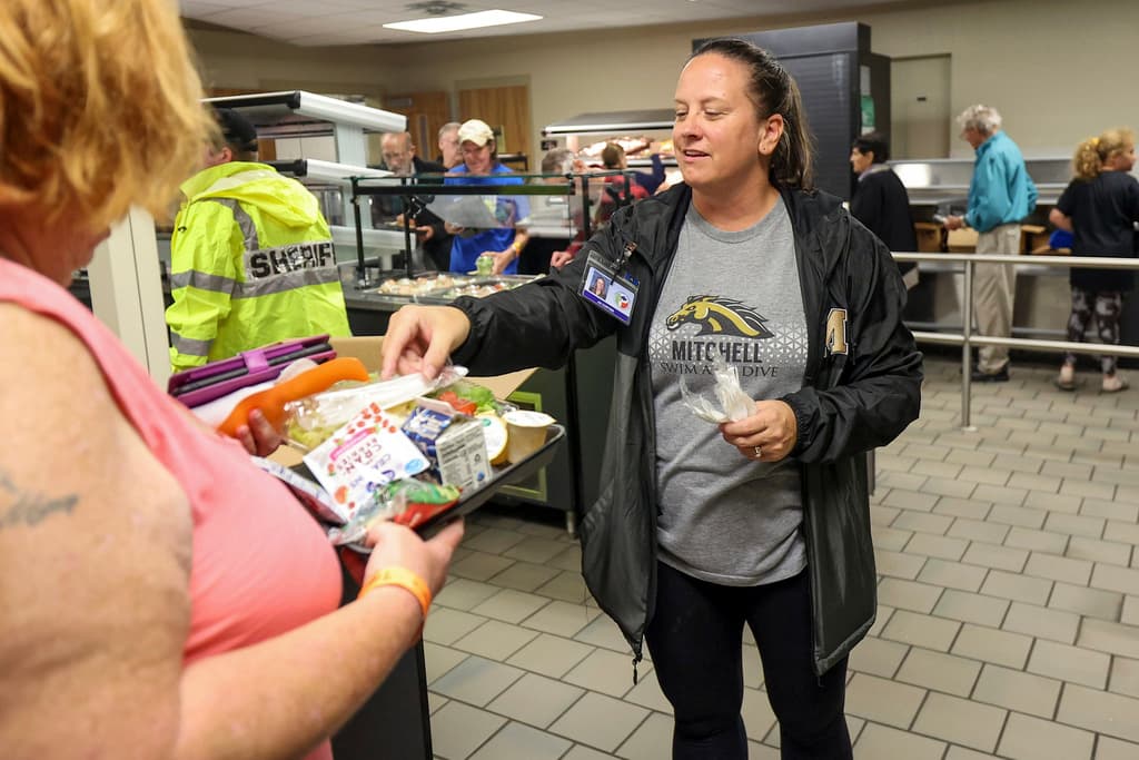 <b>Orienta a evacuados:</b> La administradora de las escuelas de Pasco, Jill Cortier, habla con un evacuado durante un servicio de comida en un refugio para huracanes en la escuela secundaria/preparatoria River Ridge en preparación para el huracán Milton, el miércoles 9 de octubre de 2024, en New Port Richey, Florida.