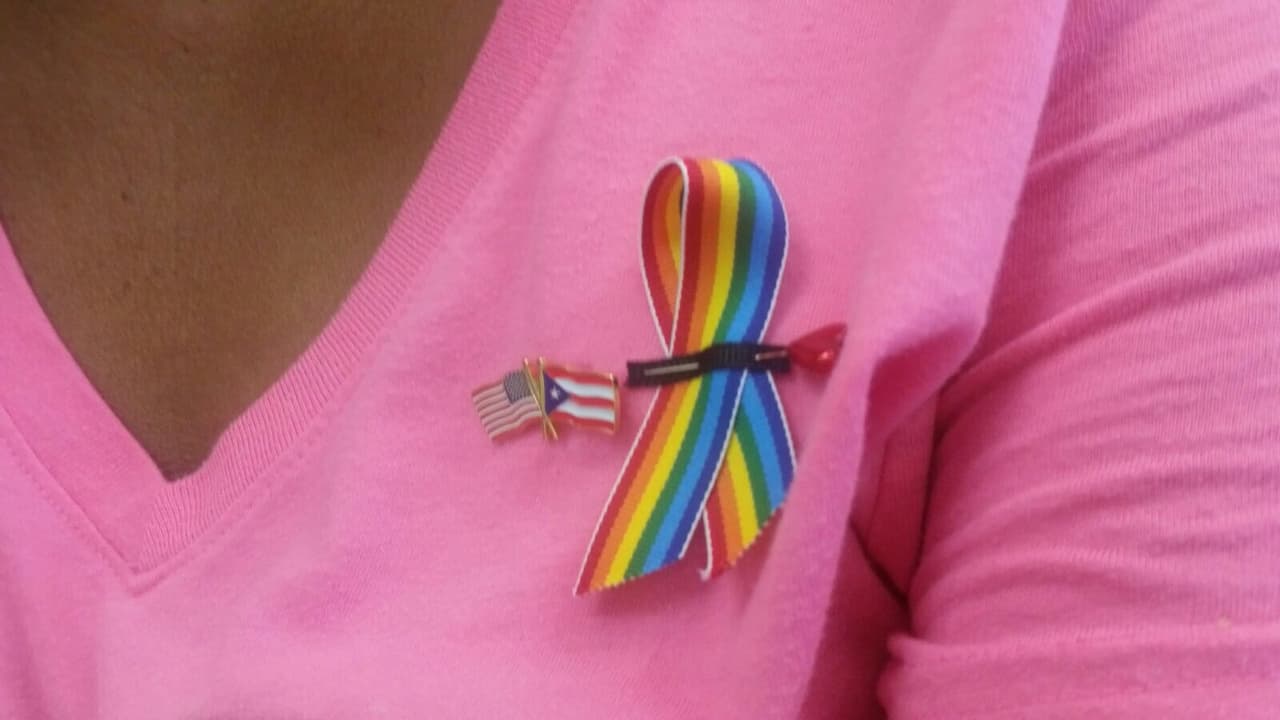 La bandera estadounidense y la puertorriqueña acompañan el lazo de orgullo LGBT en la camisa de Roxi.