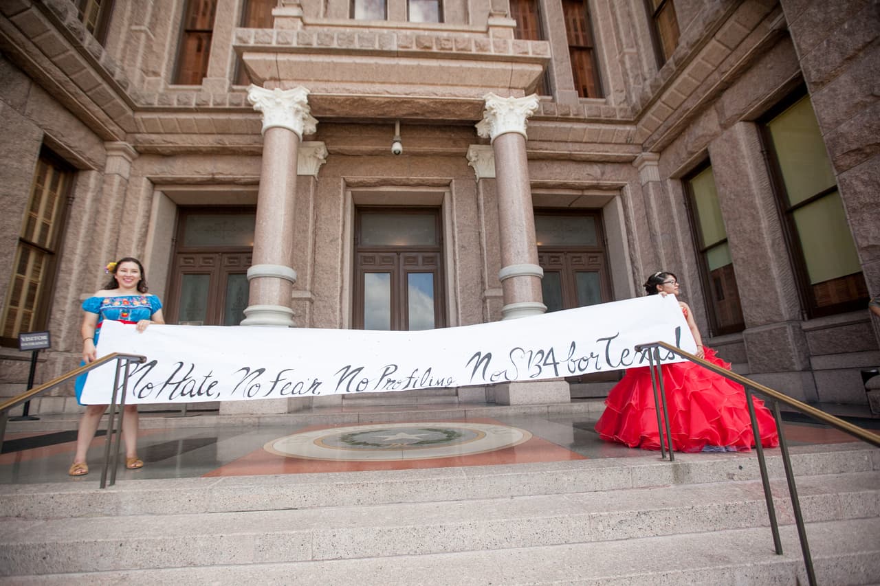 Las adolescentes llegaron al capitolio y desplegaron un cartel blanco con un mensaje escrito en inglés que reclama: "No al odio, no al miedo, no al perfil racial, no a la SB4 para Texas".