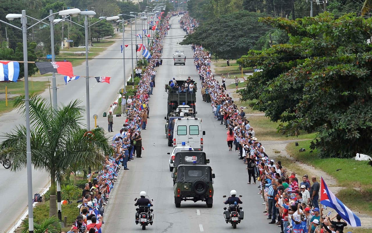 People line the road to see the convoy carrying the urn with the ashes of Cuban leader Fidel Castro as it drives through Sancti Spiritus, Cuba, on December 1, 2016 during its four-day journey across the island for the burial in Santiago de Cuba. A military jeep is taking the ashes of Fidel Castro on a four-day journey across Cuba, with islanders lining the roads to bid farewell to the late communist icon. Castro died at 90 on November 25, 2016 and will be buried in the eastern city of Santiago de Cuba on Sunday. / AFP / PEDRO PARDO (Photo credit should read PEDRO PARDO/AFP/Getty Images)