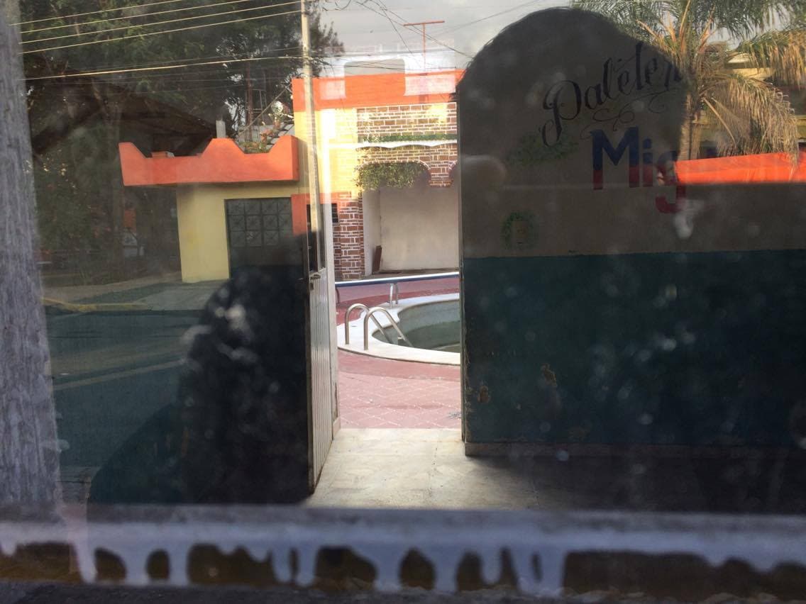 El exterior de esta misma casa no se aprecian detalles extravagantes, pero por medio de una ventana rota se alcanza a ver que la propiedad cuenta con varias habitaciones y un enorme patio con una alberca.