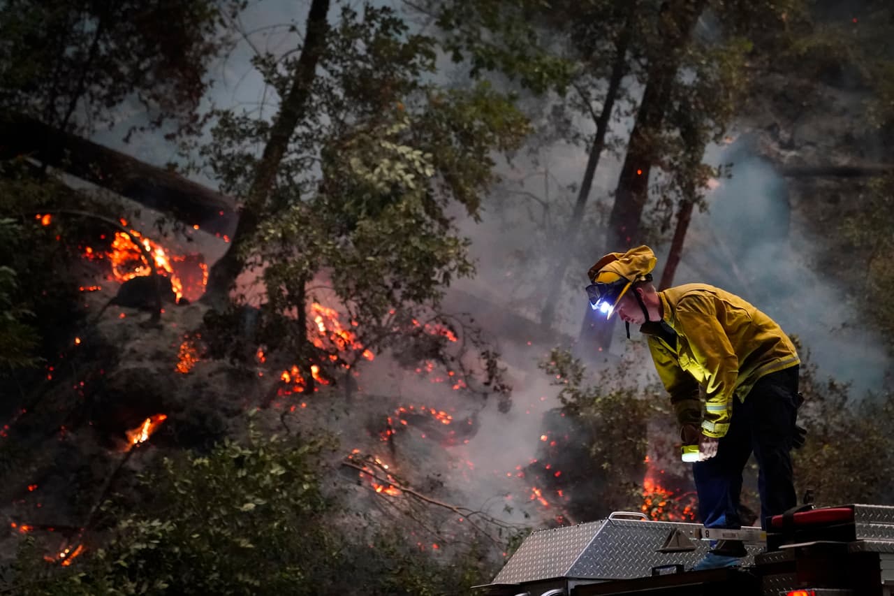 Ben Slaughter, un bombero del Departamento de Bomberos de Boulder Creek, se para sobre un camión de bomberos a lo largo de la autopista 9
<b>mientras monitorea las llamas del incendio </b>del CZU August Lightning Complex Fire en Boulder Creek, California.
<br>