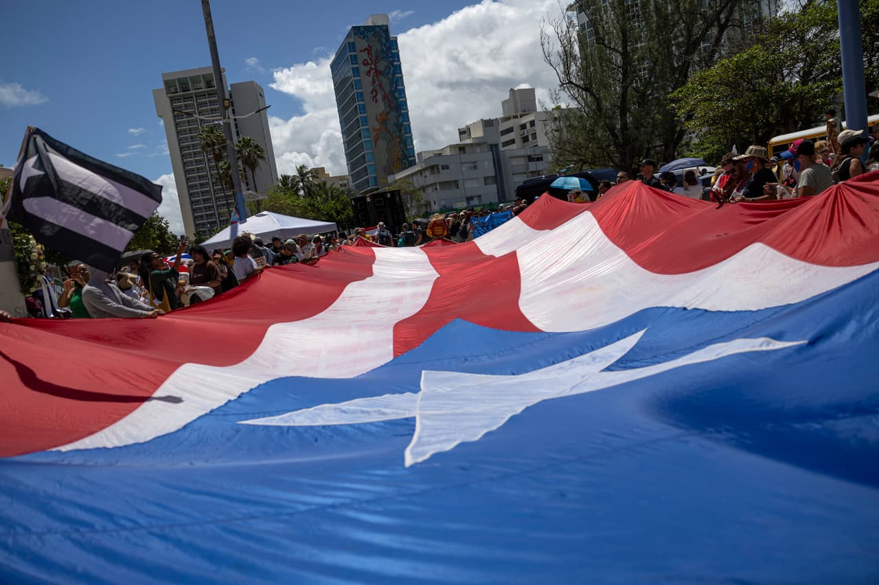 <b>Marcha en San Juan con bandera gigante de Puerto Rico.</b> Manifestantes recorrieron la capital portando una bandera de gran tamaño durante la protesta.
<br>