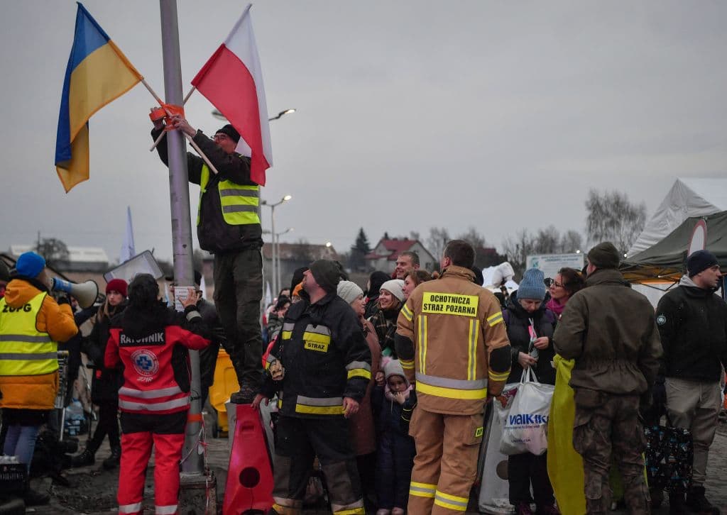 Un voluntario ajusta las banderas polacas y ucranianas mientras los refugiados esperan su transporte después de cruzar la frontera entre Ucrania y Polonia en el cruce fronterizo en Medyka, sureste de Polonia, el 9 de marzo de 2022.