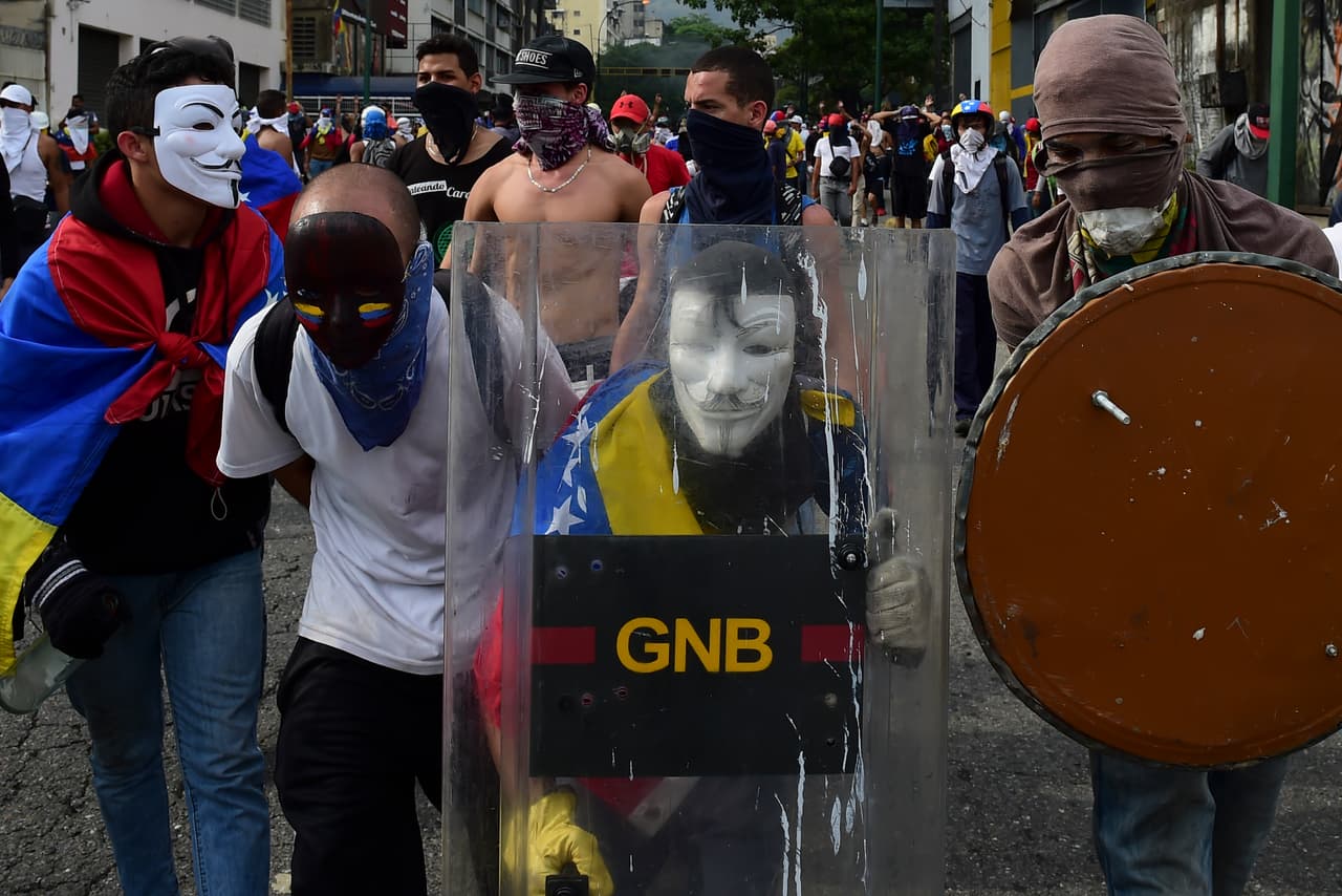A masked opponent carries a shield he took from the Bolivarian National Guard. April 19, 2017.