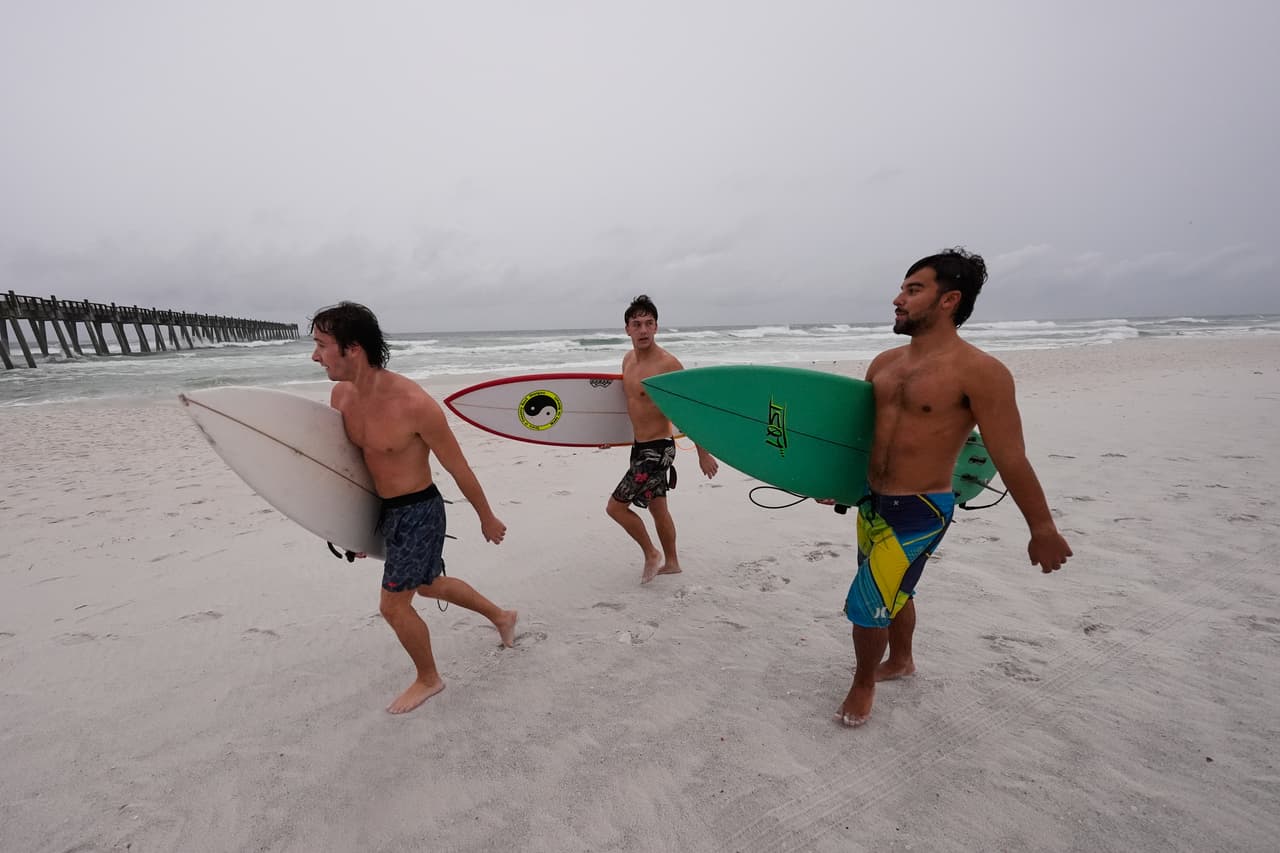 Los surfistas caminan por la playa mientras el huracán Isaias se acerca a Pensacola Beach, Florida, el viernes 9 de octubre de 2026.