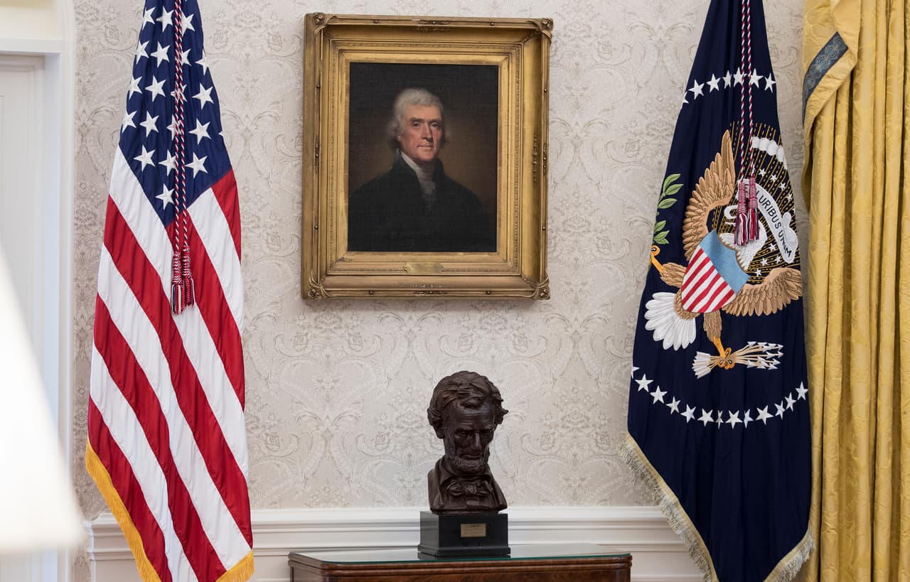 El busto de Abraham Lincoln y un retrato de Thomas Jefferson flanqueados por una bandera de EEUU y otra con el sello presidencial ahora del lado derecho del escritorio del Presidente. El busto de Winston Churchill ocupó este espacio durante un tiempo luego de la llegada de Donald Trump a la Casa Blanca.