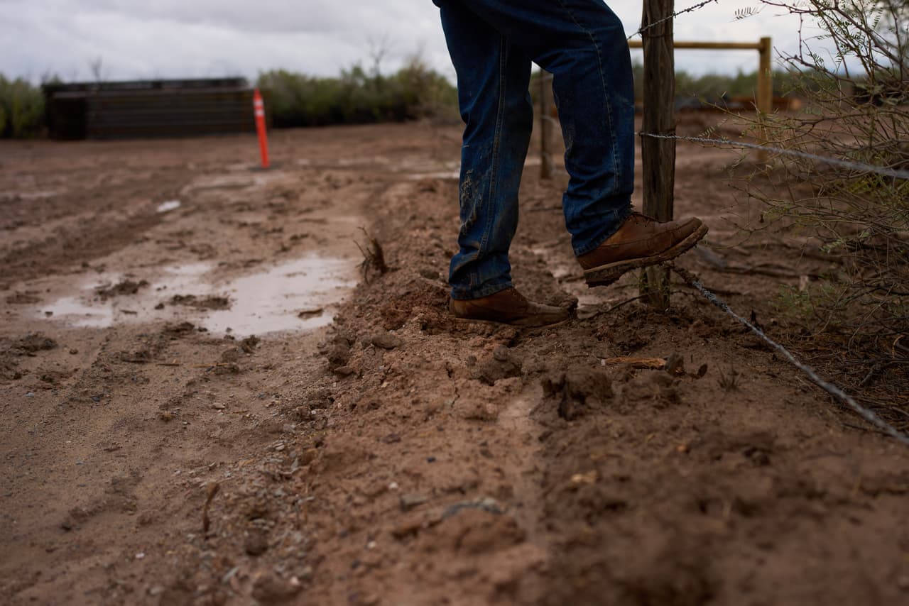 Bill Addington se quita el barro de las botas mientras visita una zona de construcción del muro fronterizo cerca de su propiedad, el miércoles 23 de septiembre de 2026, cerca de Sierra Blanca, Texas.