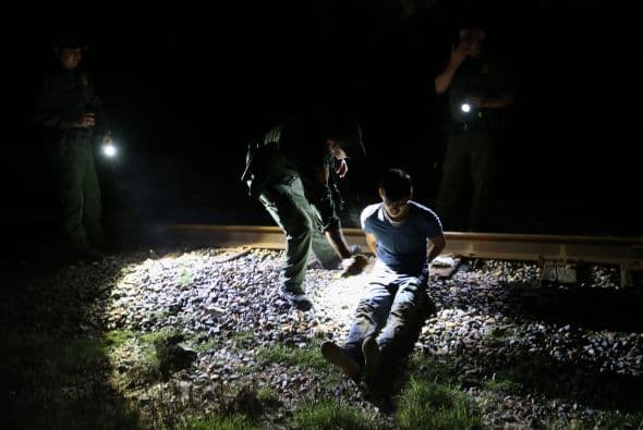 Un agente de la Patrulla Fronteriza detiene a un inmigrante indocumentado a lo largo de las vías del tren cerca del Río Bravo en la frontera México-Estados Unidos.