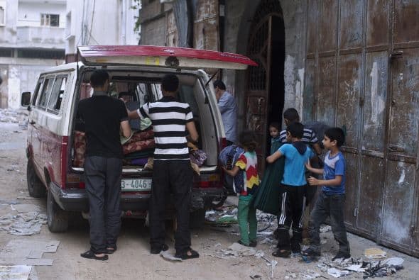 La familia Habibi, que había huido de su casa en busca de seguridad durante los enfrentamientos, desempaca su coche al llegar a casa en el barrio de Shejaiya.