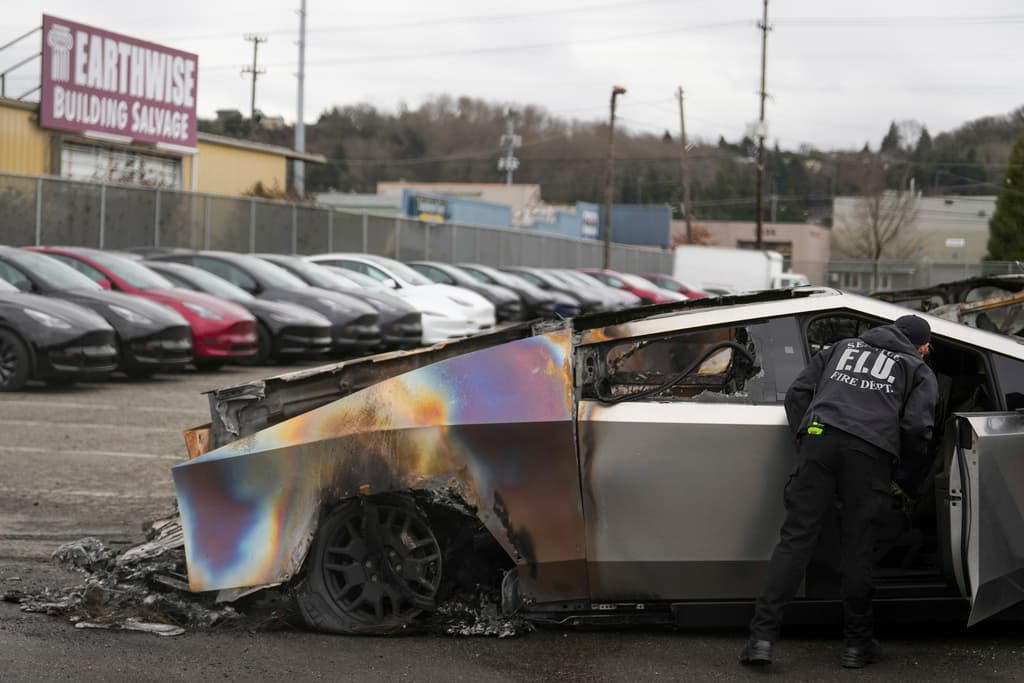 Un miembro del Departamento de Bomberos de Seattle inspecciona un Tesla Cybertruck quemado en un lote de Tesla en Seattle, el lunes 10 de marzo de 2025. (AP Foto/Lindsey Wasson)