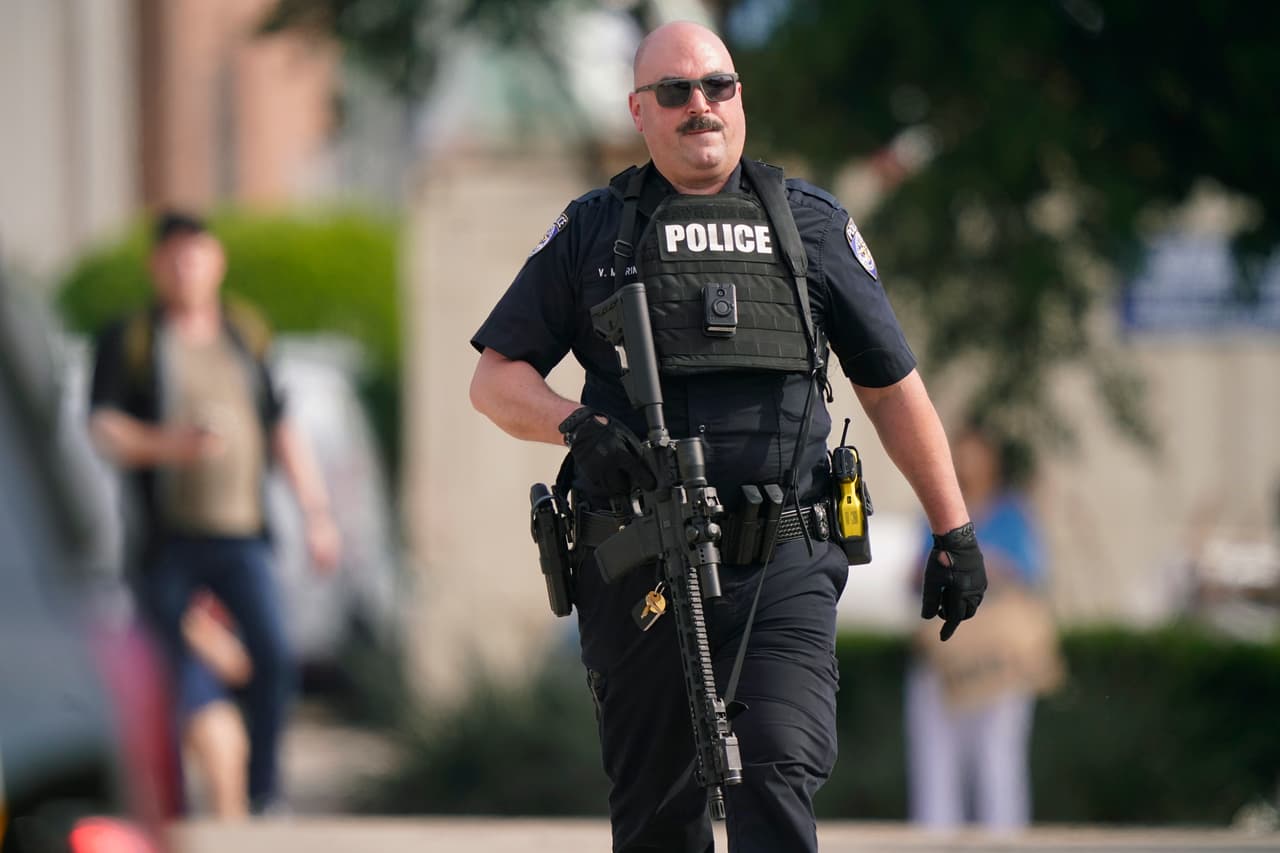 Un oficial de la ley lleva un rifle mientras las personas son evacuadas del centro comercial Allen Premium Outlets donde ocurrió un tiroteo el sábado 6 de mayo de 2023 en Allen, Texas.