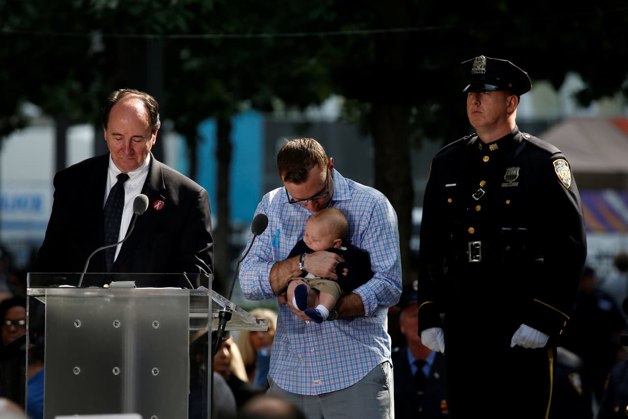 Un hombre carga a un bebé mientras son leídos, uno a uno, los nombres de los fallecidos ese 11 de septiembre. (Brendan McDermid/Reuters)