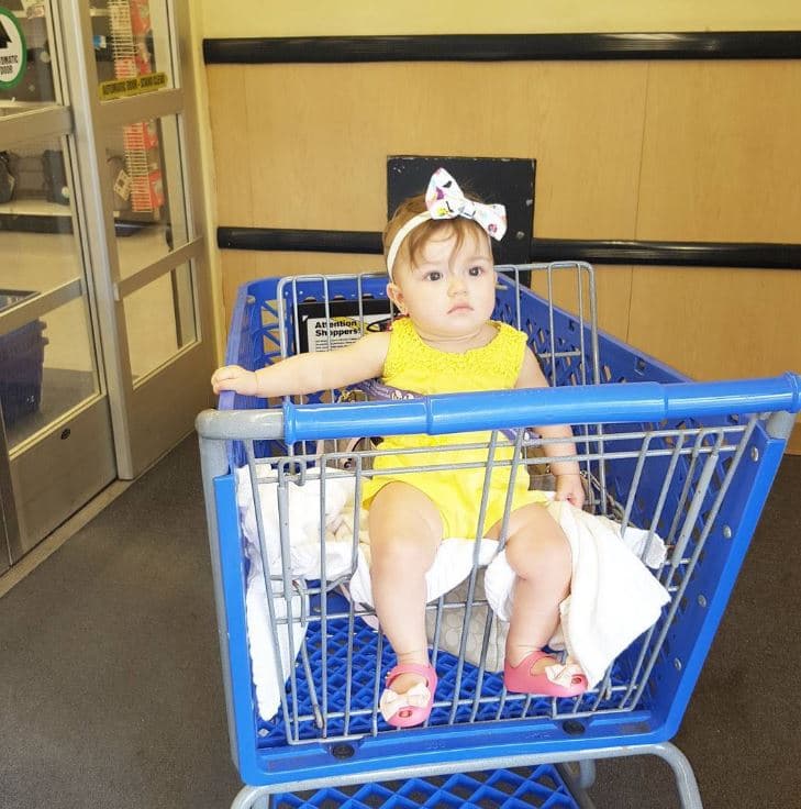 Como toda una nena grande, ya Kamilia va sentadita en el asiento del carrito de compras.