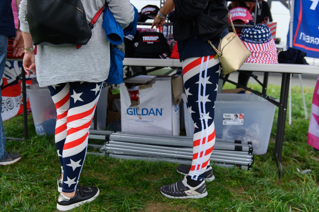 Simpatizantes de Trump con vestimenta alusiva a la bandera de Estados Unidos esperan el momento de abordar un autobús de enlace antes del evento de campaña para el presidente.