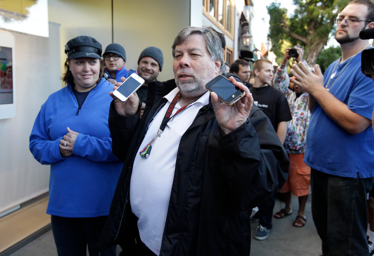 El cofundador de Apple, Steve Wozniak, muestra dos iPhones antiguos antes de comprar su nuevo iPhone 4S en la tienda Apple de Los Gatos, California, el viernes 14 de octubre de 2011. Wozniak esperó 20 horas en la fila para ser el primer cliente de Apple en la tienda de Los Gatos en comprar el nuevo iPhone 4S.