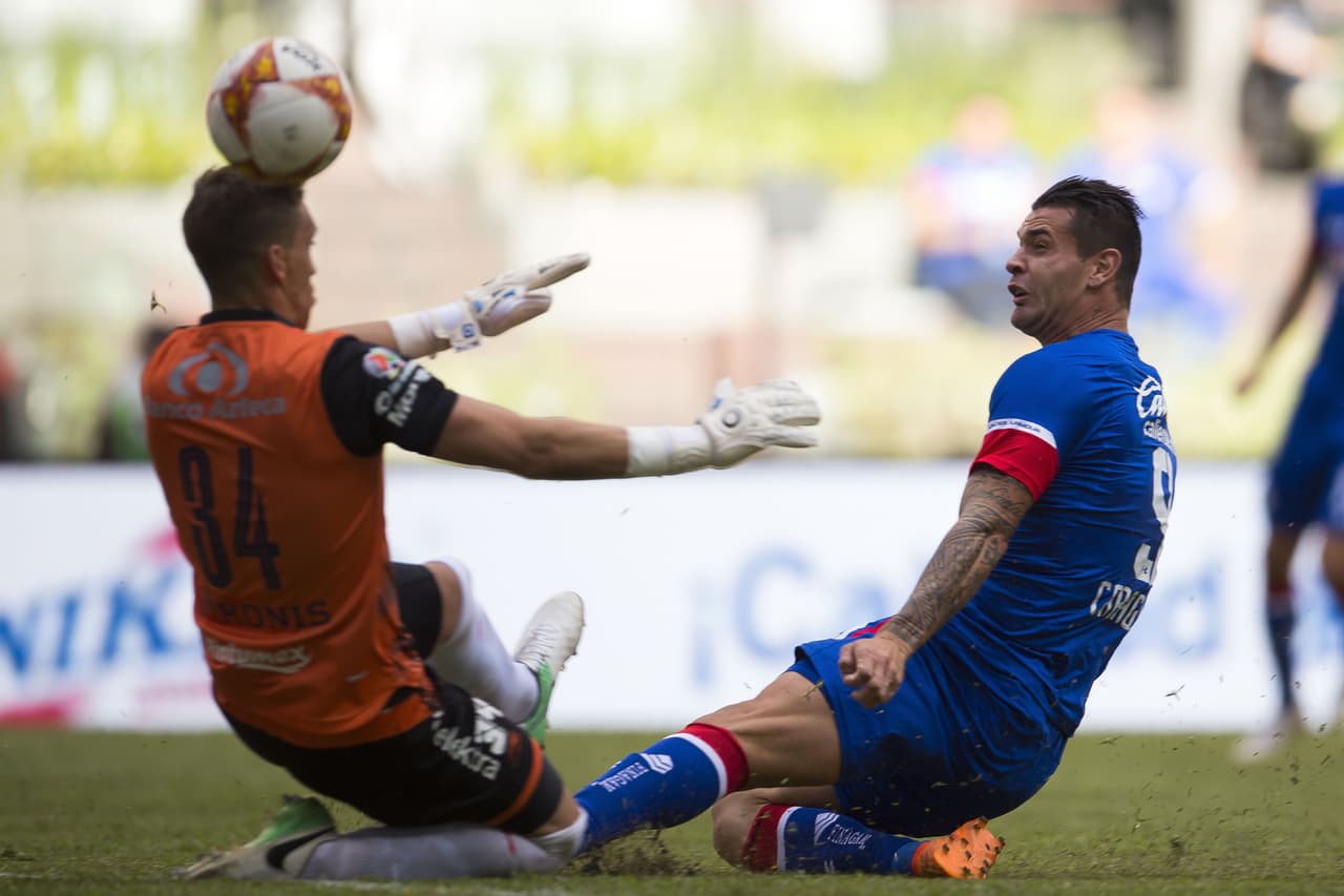 El arquero uruguayo Nicolás Vikonis (izquierda) evitó otra opción de gol de Cruz Azul, obra del delantero argentino Milton Caraglio (derecha).