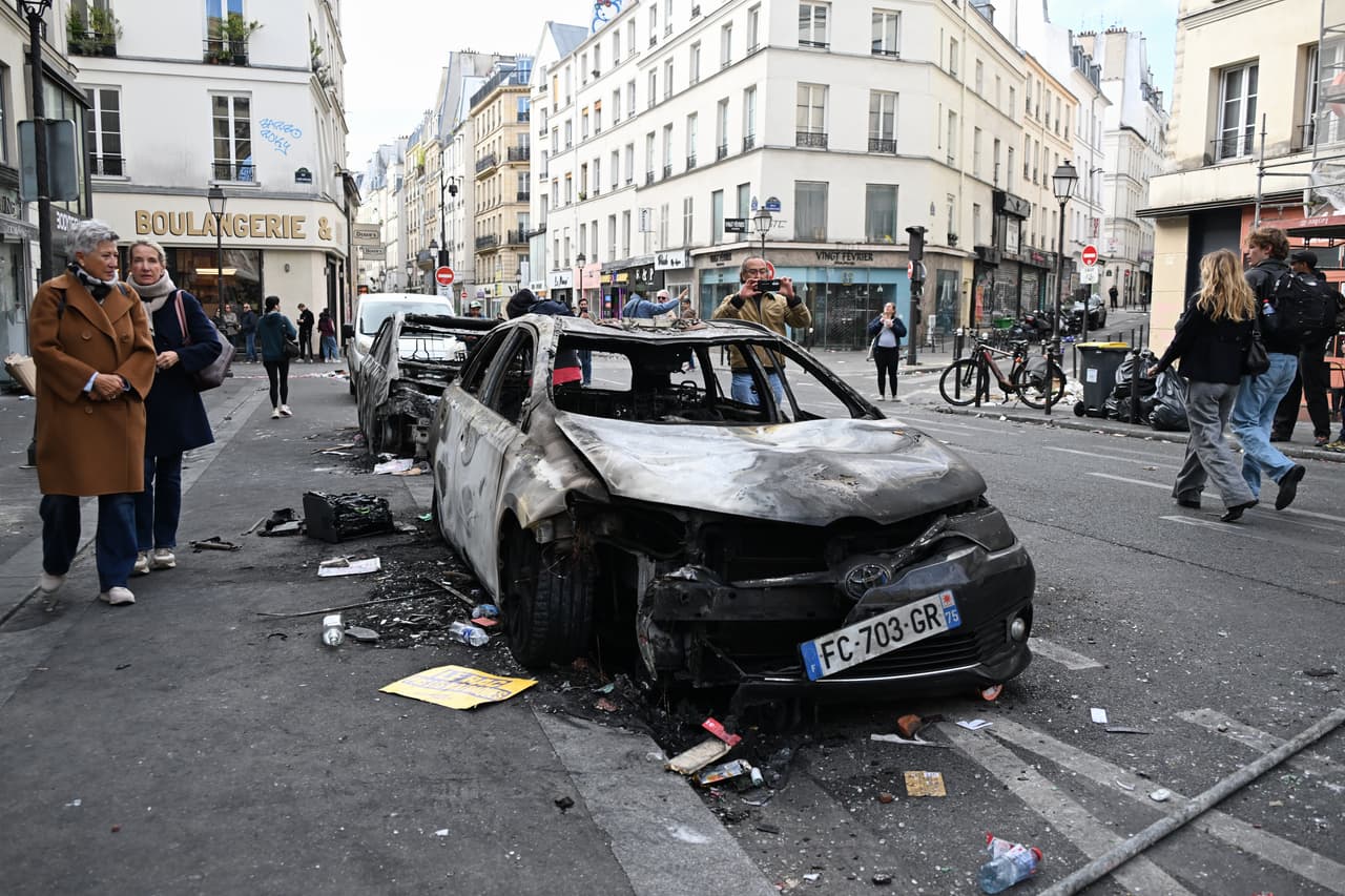 Varias personas observan coches calcinados al día siguiente de una manifestación contra el aumento del coste de la vida y en solidaridad con las reivindicaciones estudiantiles, en París, el domingo 18 de octubre de 2026.