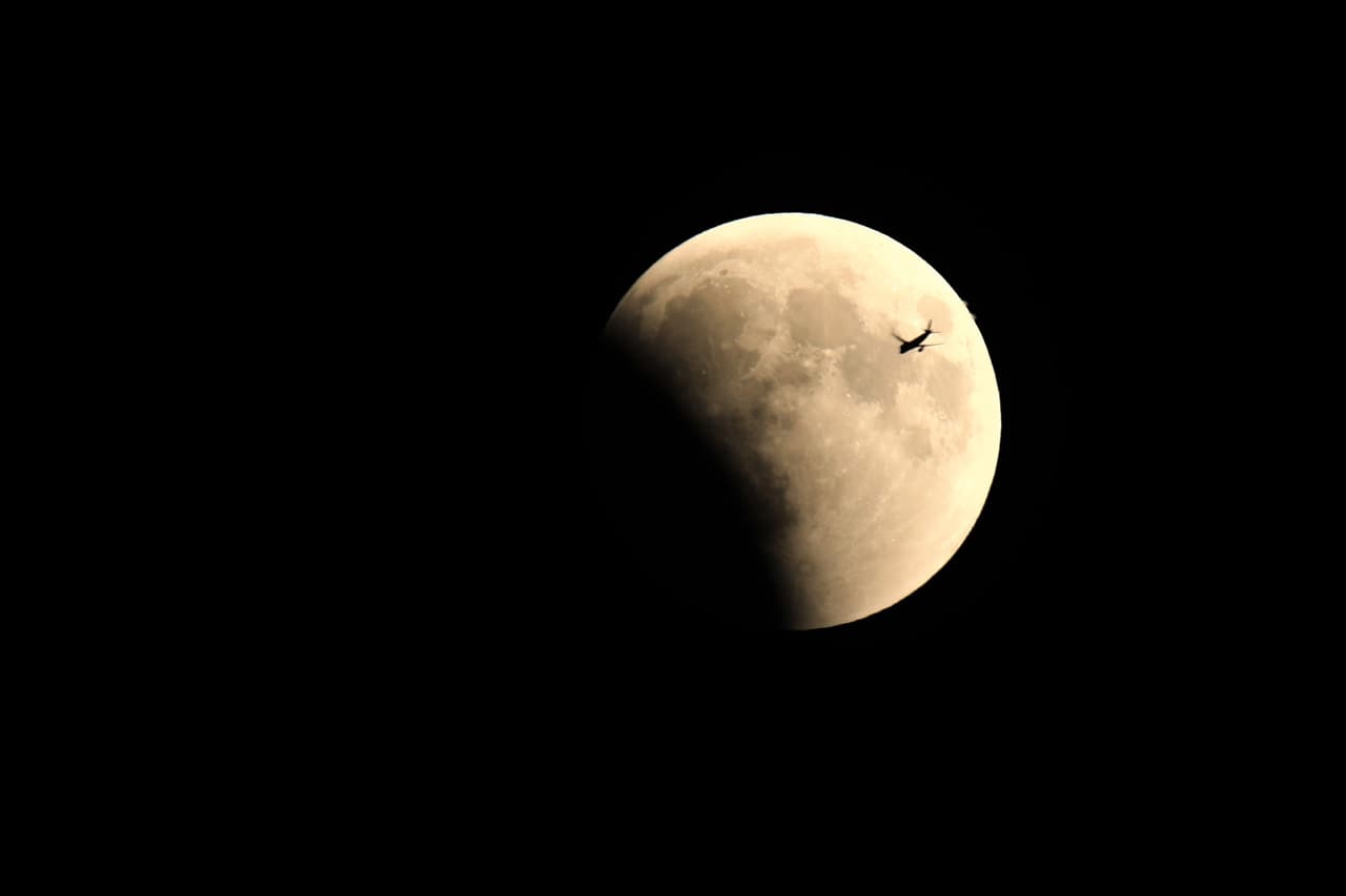 La Luna llena y un avión cuando comenzaba a oscurecerse por la sombra de la Tierra vista desde Van, Turquía.