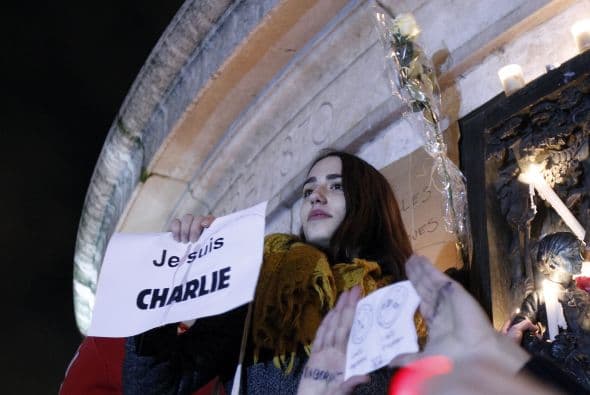 Una mujer sostiene una pancarta que dice "Yo soy Charlie" durante una vigilia en la Plaza de la República.
