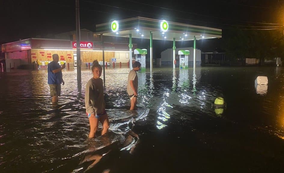 Estas personas caminan por una calle de North Myrtle Beach, en Carolina del Sur, con el agua casi hasta las rodillas luego del paso del huracán Isaías por la costa del estado.