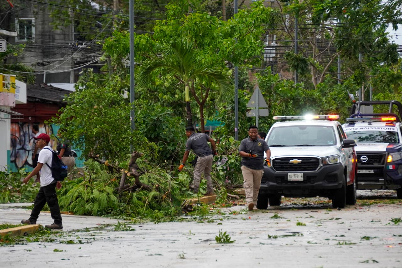 Los trabajadores de Protección Civil cortan árboles derribados por fuertes ráfagas de viento provocadas por el paso del huracán Beryl en Tulum.