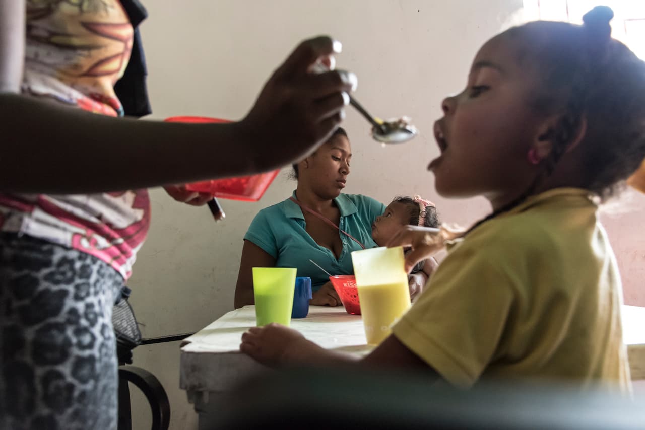 Yuleidys Flores, de 27 años, carga en brazos a su hija Fabiannys, de solo trece meses, mientras le da arroz en un comedor de beneficiencia.