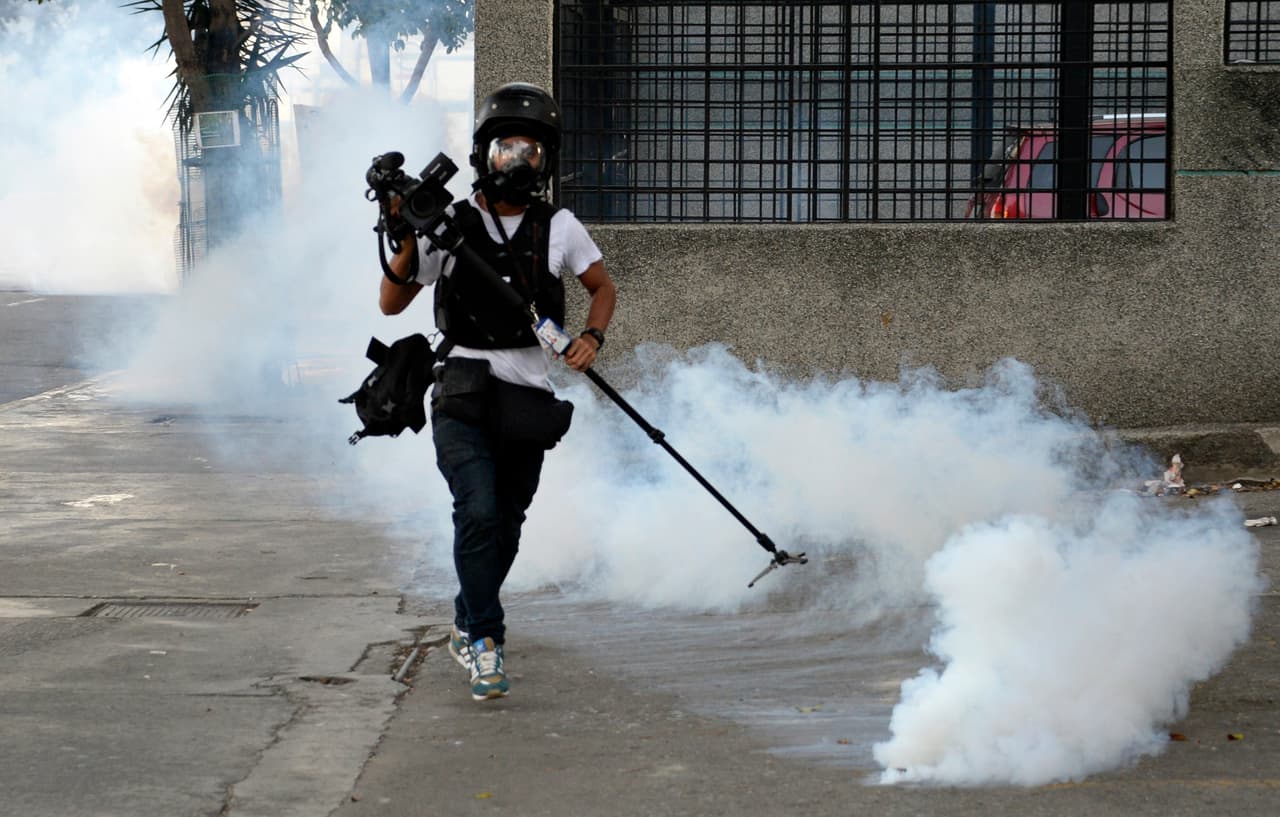 Un camarógrafo corre en medio de gas lacrimógeno en una protesta en Caracas en 2014.
