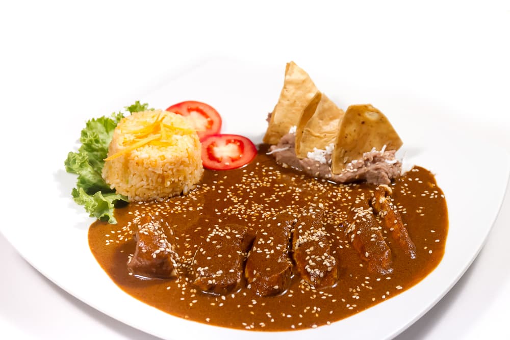 Mole Amarillo. Para cocinar un mole amarillo necesitas poner en la mesa los siguientes ingredientes: chile ancho, guajillo y costeño, tomate verde, cebolla, ajo, comino, pimienta negra, clavo y chilcoxtle. Si se sirve con pollo y hay que ponerle hoja santa, con cerdo. Después agrega cilantro y con carne res, se acompaña con cebollitas de cambray, limón, orégano, sal y rajas de chile de agua.