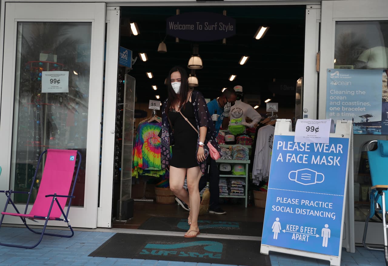 A customers walks past a sign reading, ' please wear face mask,' on May 18, 2020 in Fort Lauderdale, Florida.