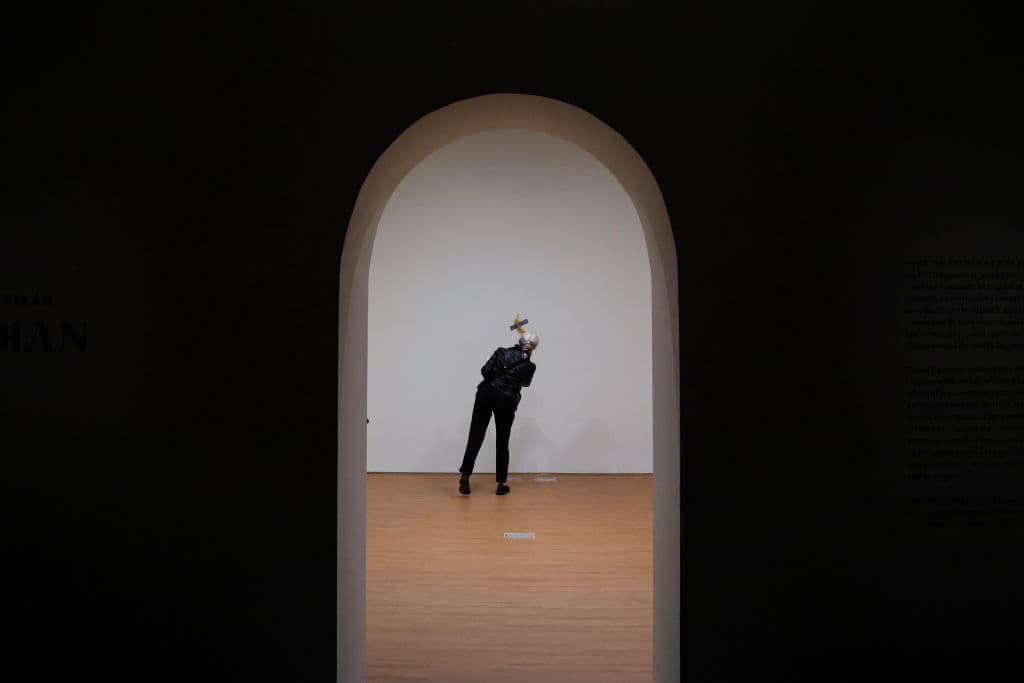 A journalist takes a look at Italian visual artist Maurizio Cattelan's duct-taped Banana entitled "Comedian," displayed during a media preview at Sotheby's in New York, on November 8, 2024. A work by Belgian painter René Magritte, another by American Ed Ruscha and a vulgar banana are the stars that could set records for their authors in the art auctions that begin this week in New York in a market that hopes to overcome last year's slump. The two main houses Sotheby's and Christie's compete from November 18 with a rich offer in which the greatest exponents of 20th and 21st century painting abound, such as Picasso, Magritte, Matisse, Miró, Kankinsky, Moore, Ruscha, Basquiat, Carrington, Rothko, Lichtenstein, Giacometti or Haring. (Photo by kena betancur / AFP) / RESTRICTED TO EDITORIAL USE - MANDATORY MENTION OF THE ARTIST UPON PUBLICATION - TO ILLUSTRATE THE EVENT AS SPECIFIED IN THE CAPTION / TO GO WITH AFP STORY BY Ana FERNANDEZ: "Magritte, Rucha and... a banana, in a bid to set new records at New York auctions" (Photo by KENA BETANCUR/AFP via Getty Images)