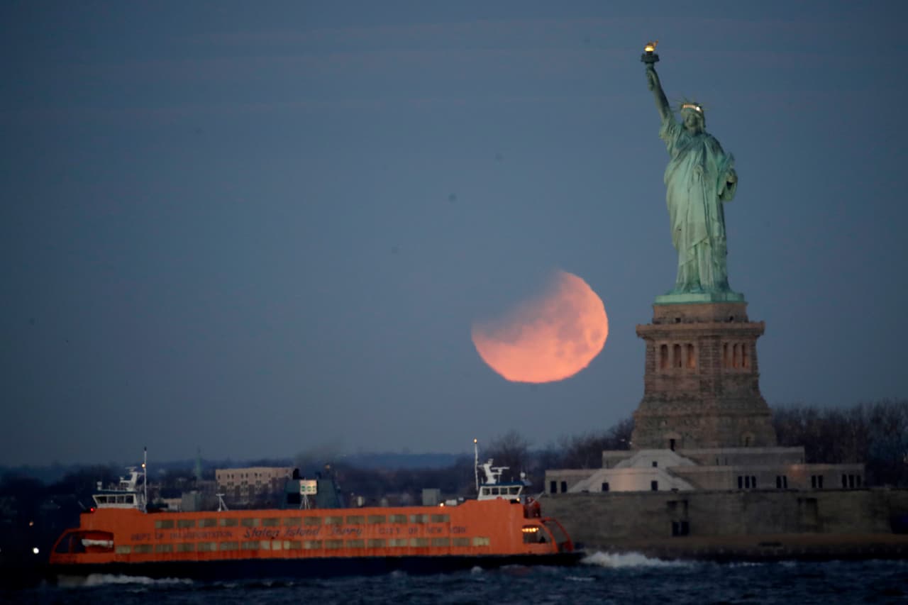 La superluna eclipsada detrás de la estatua de la libertad en Nueva York.