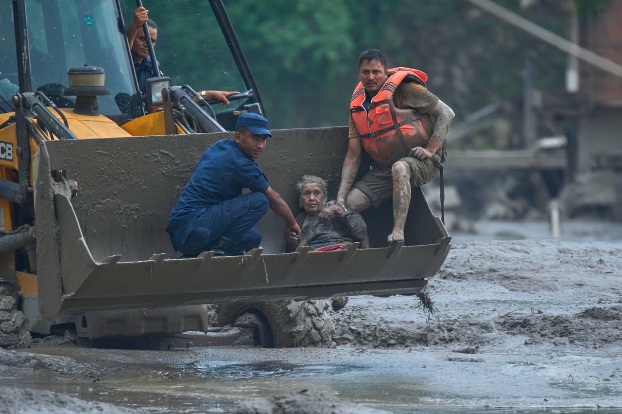 Los rescatistas utilizan una excavadora para trasladar a una víctima de las inundaciones repentinas a un lugar seguro a lo largo del río Trishuli.