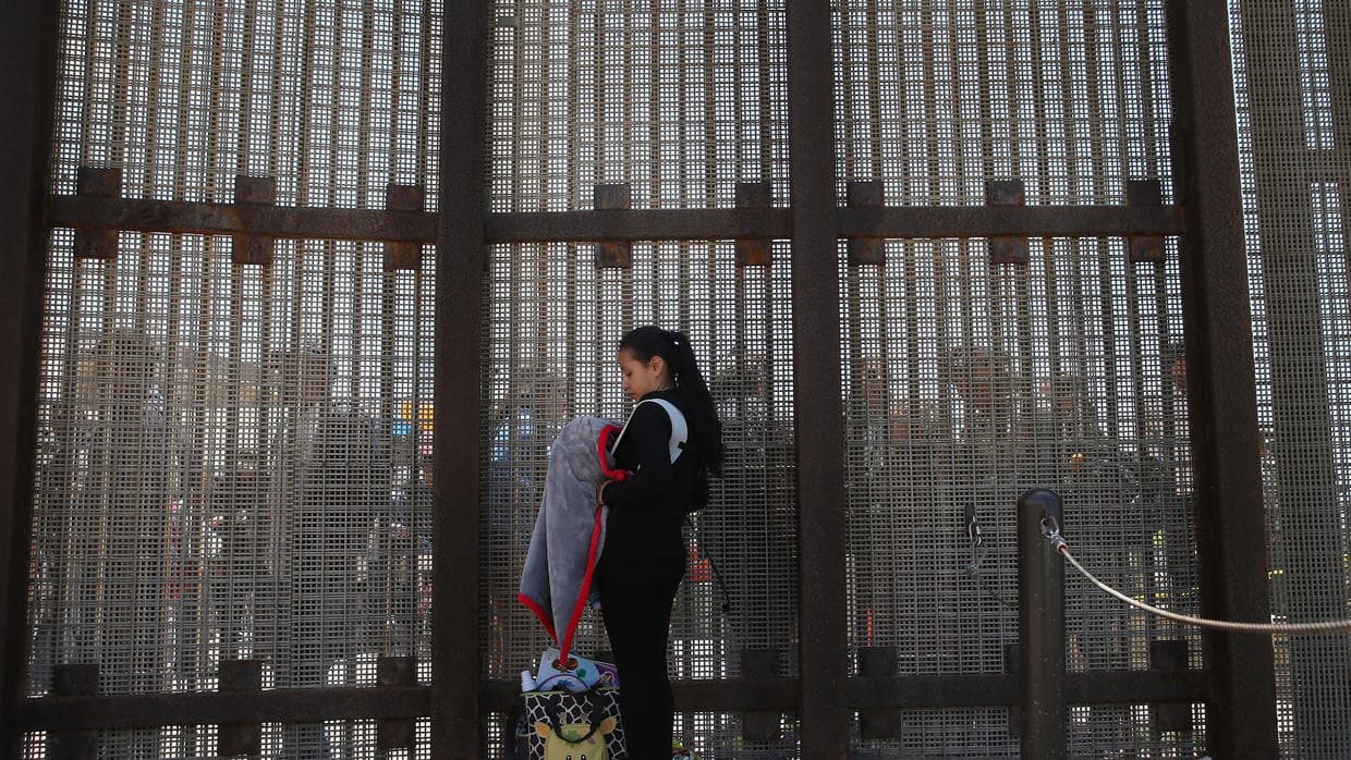 Karen Herrera, 23, and her infant son Ivan, on the border in San Diego, California, talking to family members on the Mexican side.