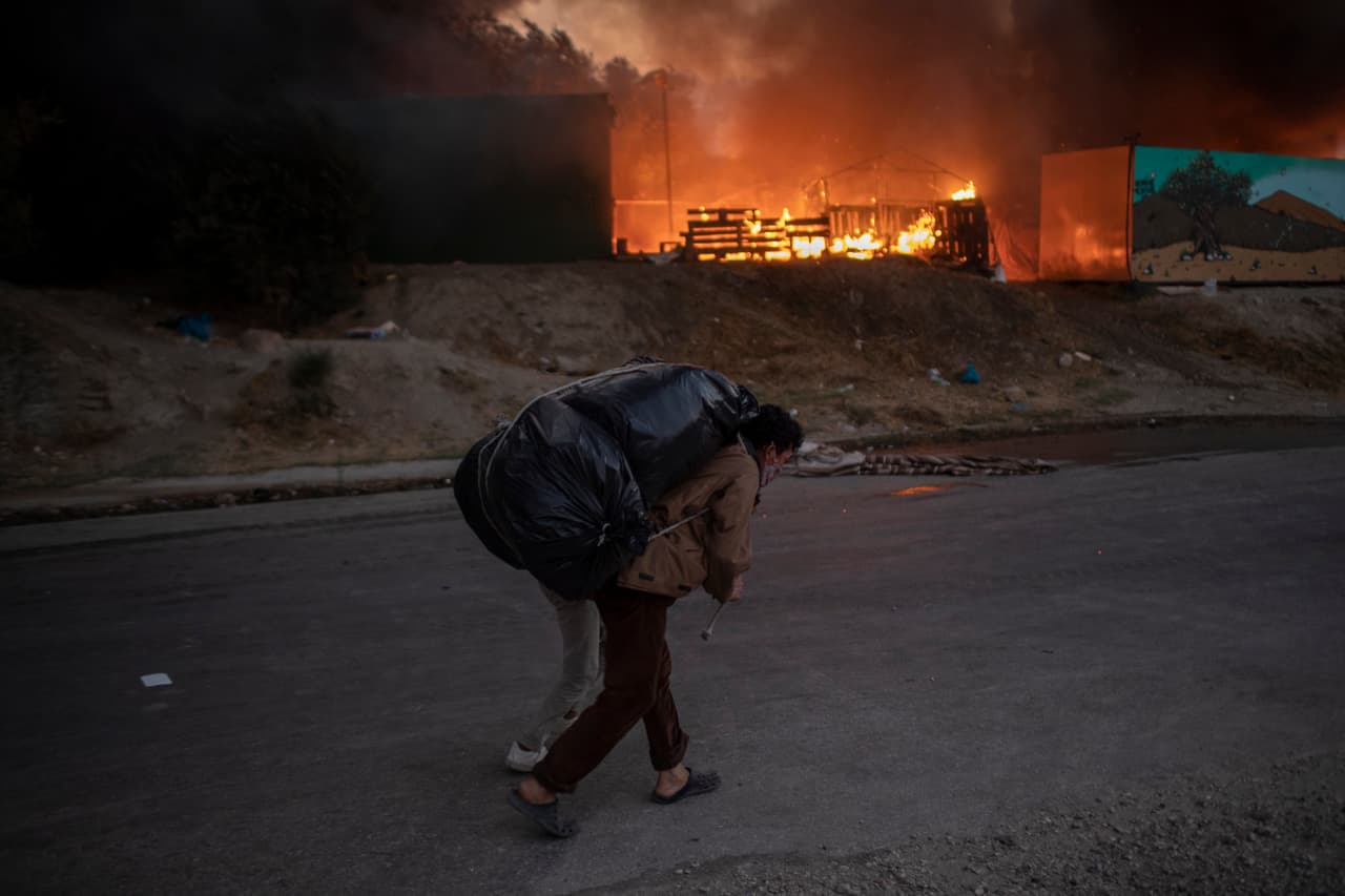 Migrants flee from the Moria refugee camp during a second fire, on the northeastern Aegean island of Lesbos, Greece, on Wednesday, Sept. 9, 2020. Fire struck again Wednesday night in Greece's notoriously overcrowded refugee camp on the island of Lesbos, a day after a blaze swept through it and left thousands in need of emergency shelter. The fires caused no injuries, but they renewed criticism of Europe's migration policy. (AP Photo/Petros Giannakouris)