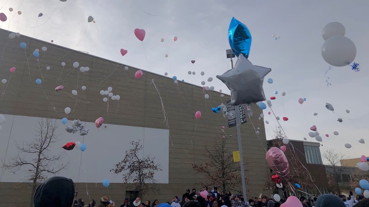 Estudiantes, vestidos de azul y blanco, solatron globos en un acto de memoria por la víctima de la violencia en La Villita.