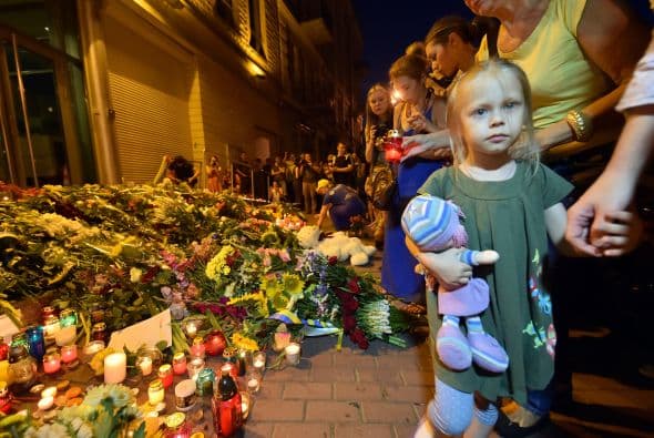 Personas dejan ramos de flores en conmemoración de las víctimas del avión estrellado de Malaysia Airlines al este de Ucrania frente de la embajada de Holanda en Kiev.