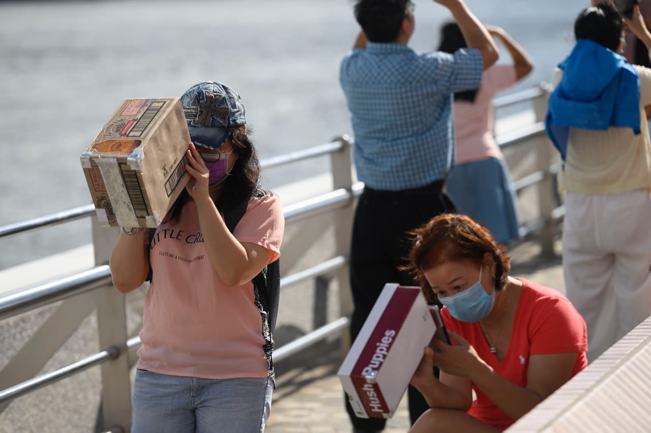 Mujeres en Hong Kong observan el eclipse parcial de sol utilizando unas cajas con agujeros.